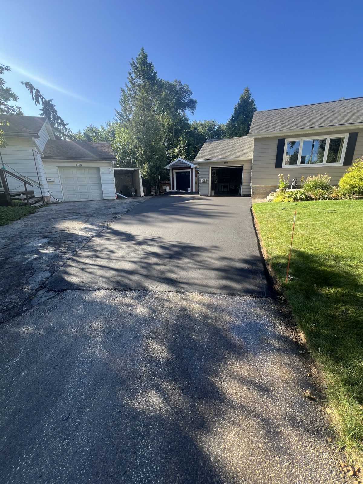 Newly paved asphalt driveway leading to two garages of a residential home in the GTA on a sunny day