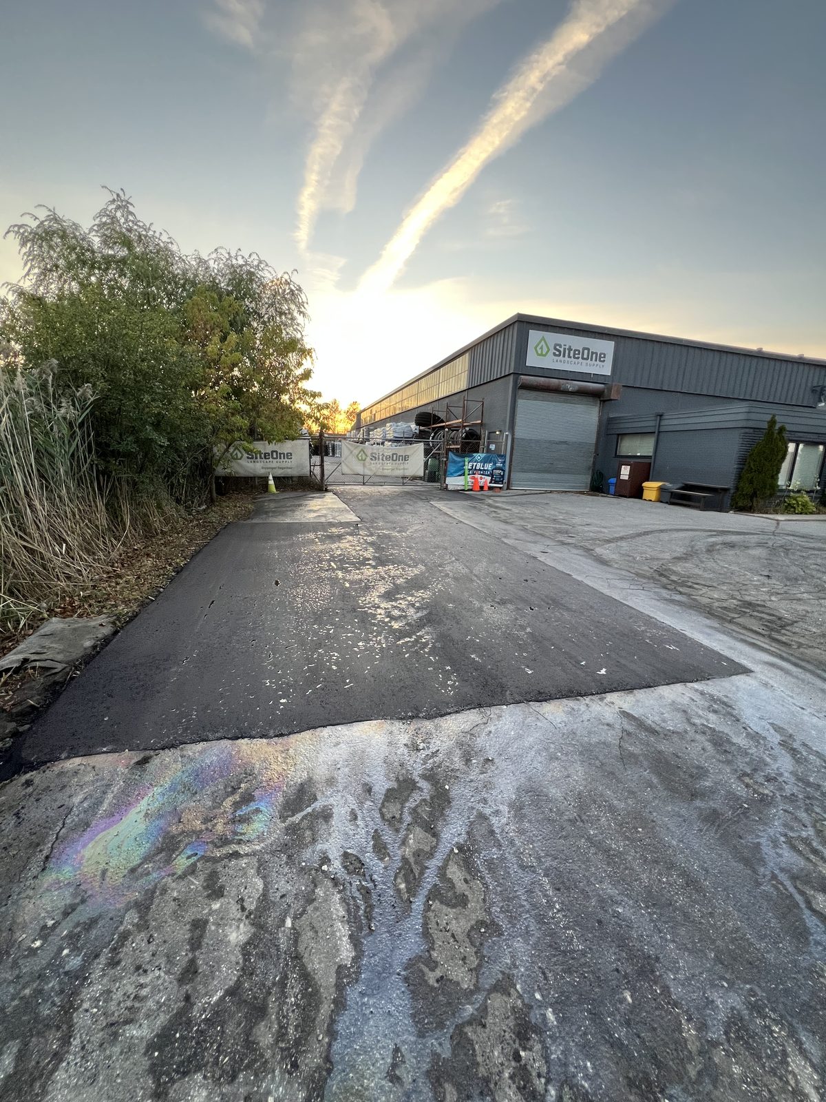 Freshly paved asphalt patch repair in a commercial lot at a SiteOne supply building in the Greater Toronto Area