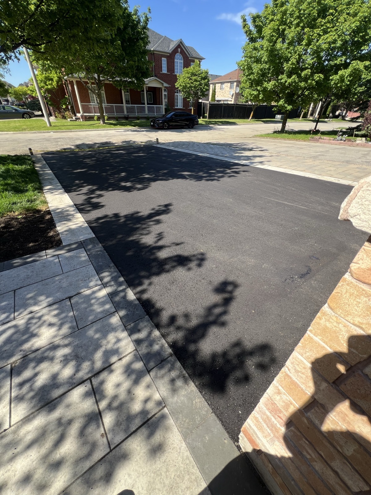 Freshly paved residential asphalt driveway beside a brick home in the GTA