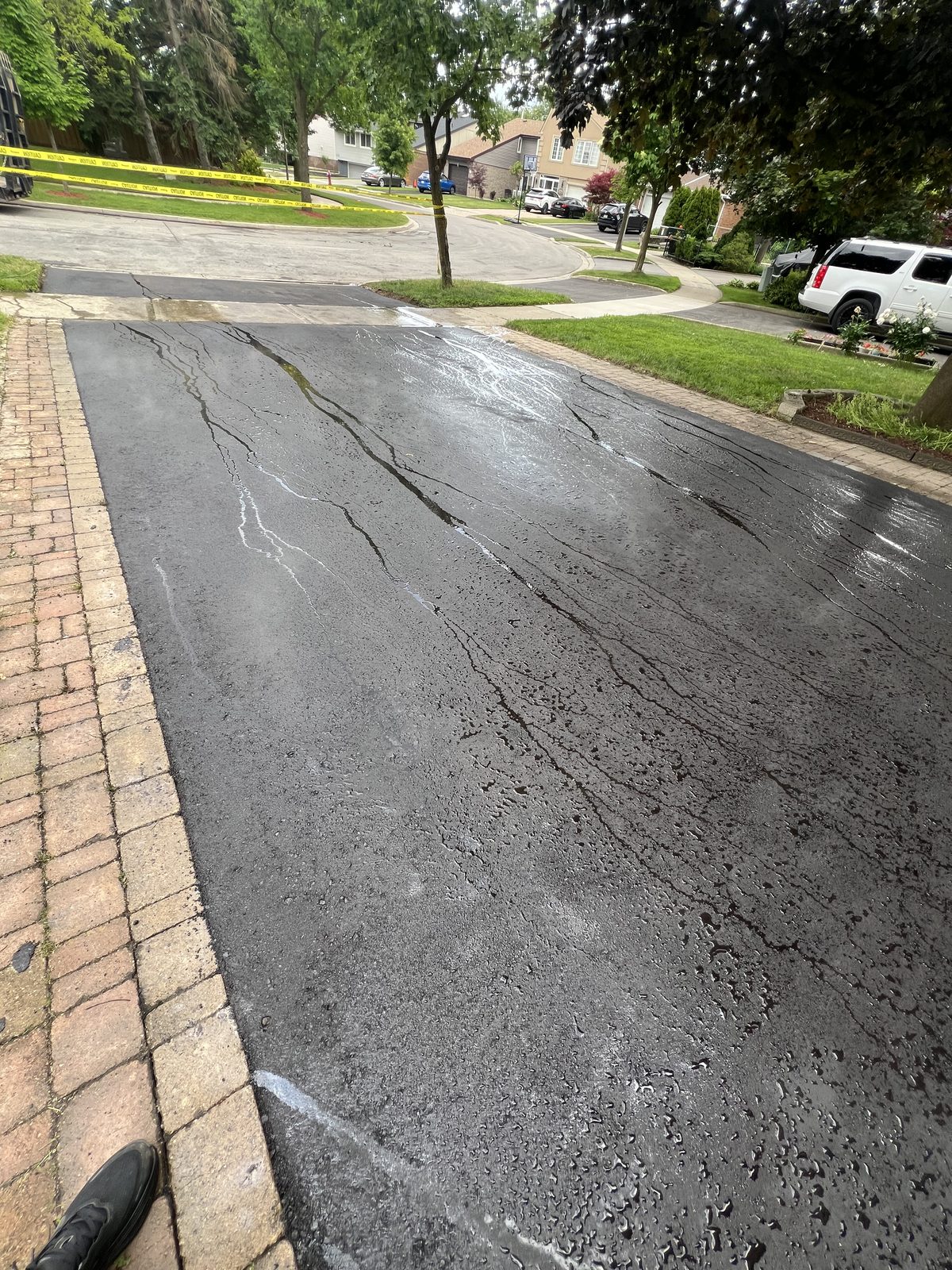 Freshly sealcoated asphalt driveway with brick paver borders in a GTA residential neighbourhood