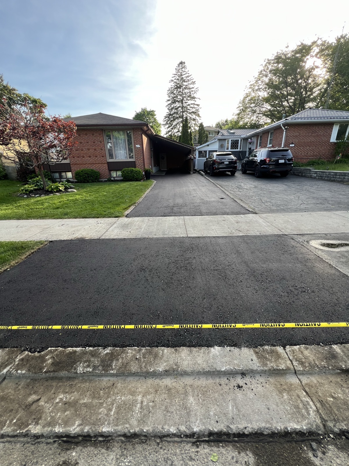 Freshly resurfaced asphalt driveway with caution tape