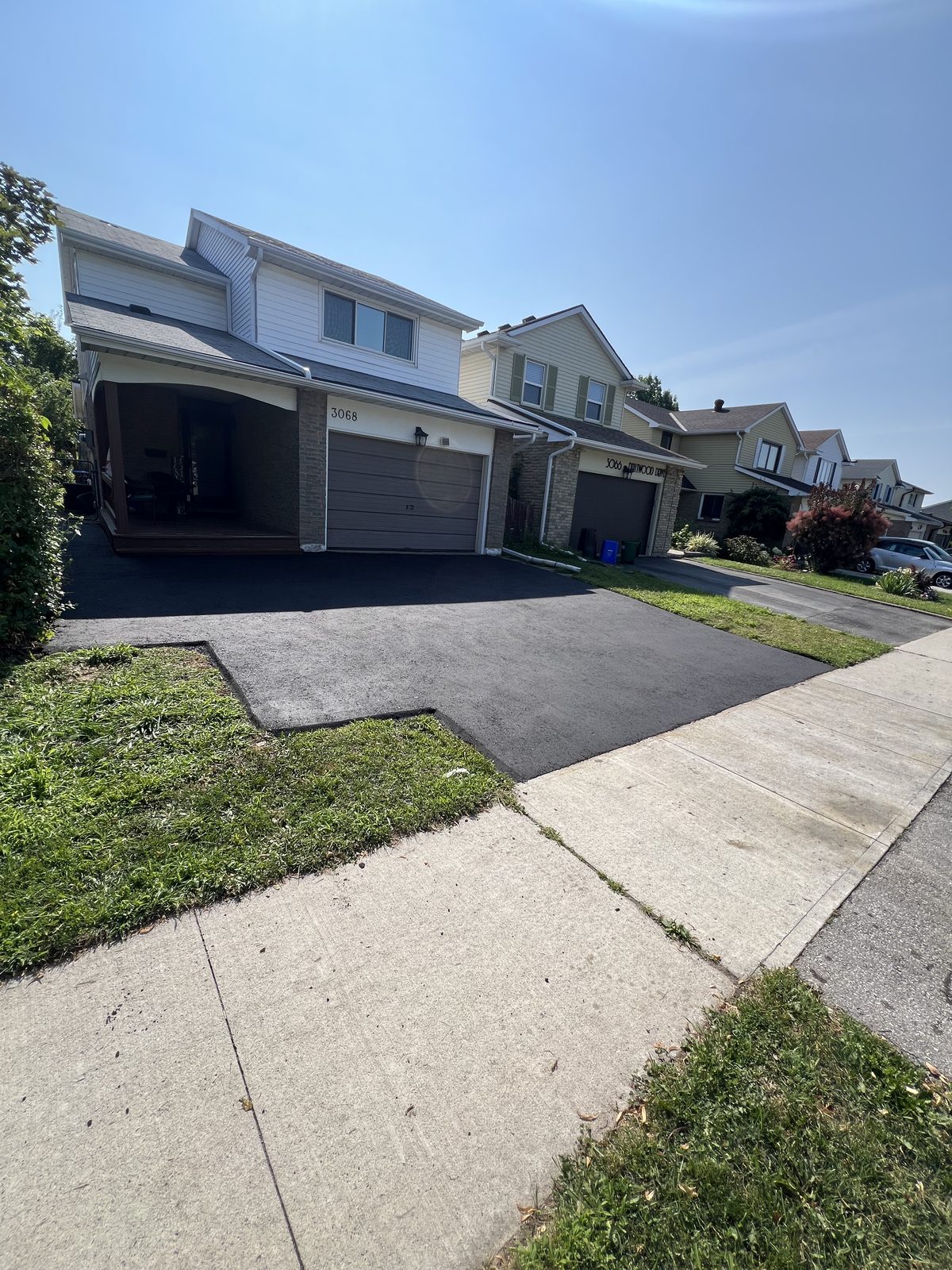 Newly paved smooth black asphalt residential driveway leading to a two-car garage in the GTA