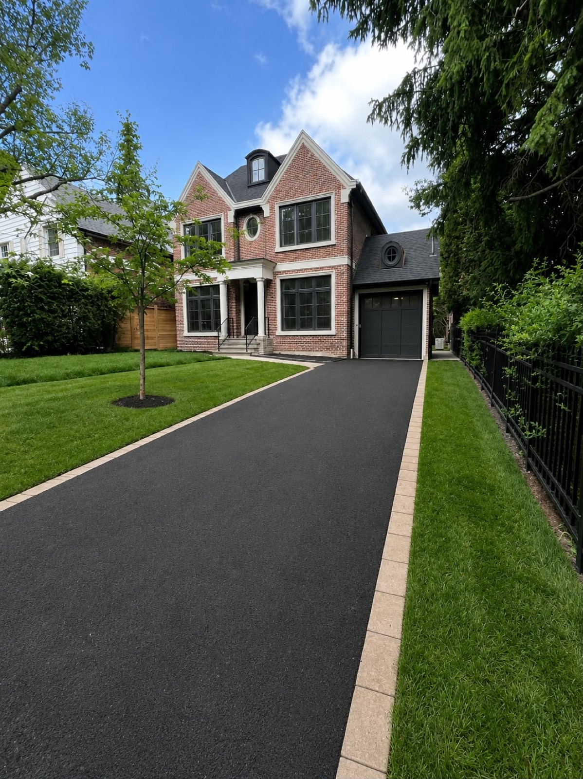 Premium asphalt driveway with a grey paver border at a brick home in the GTA