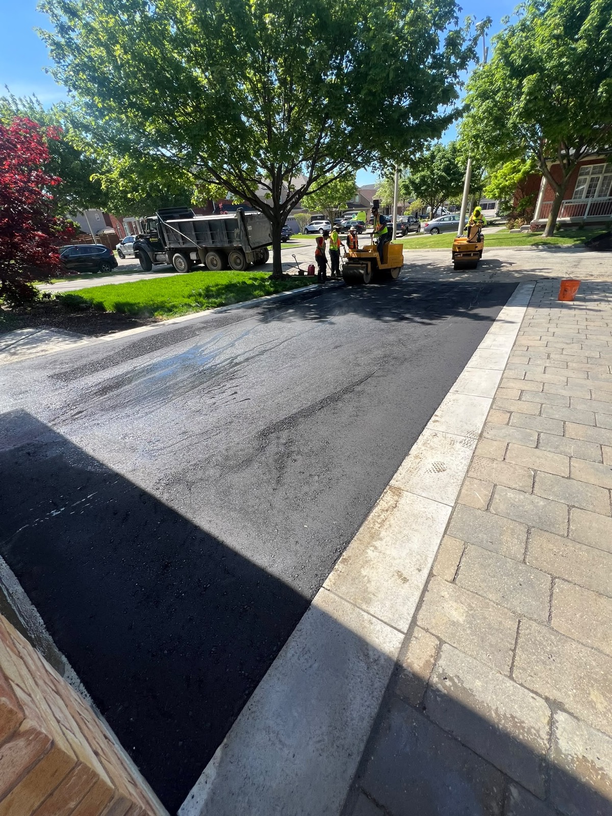 Magnum crew resurfacing a residential road in the GTA with roller and paver